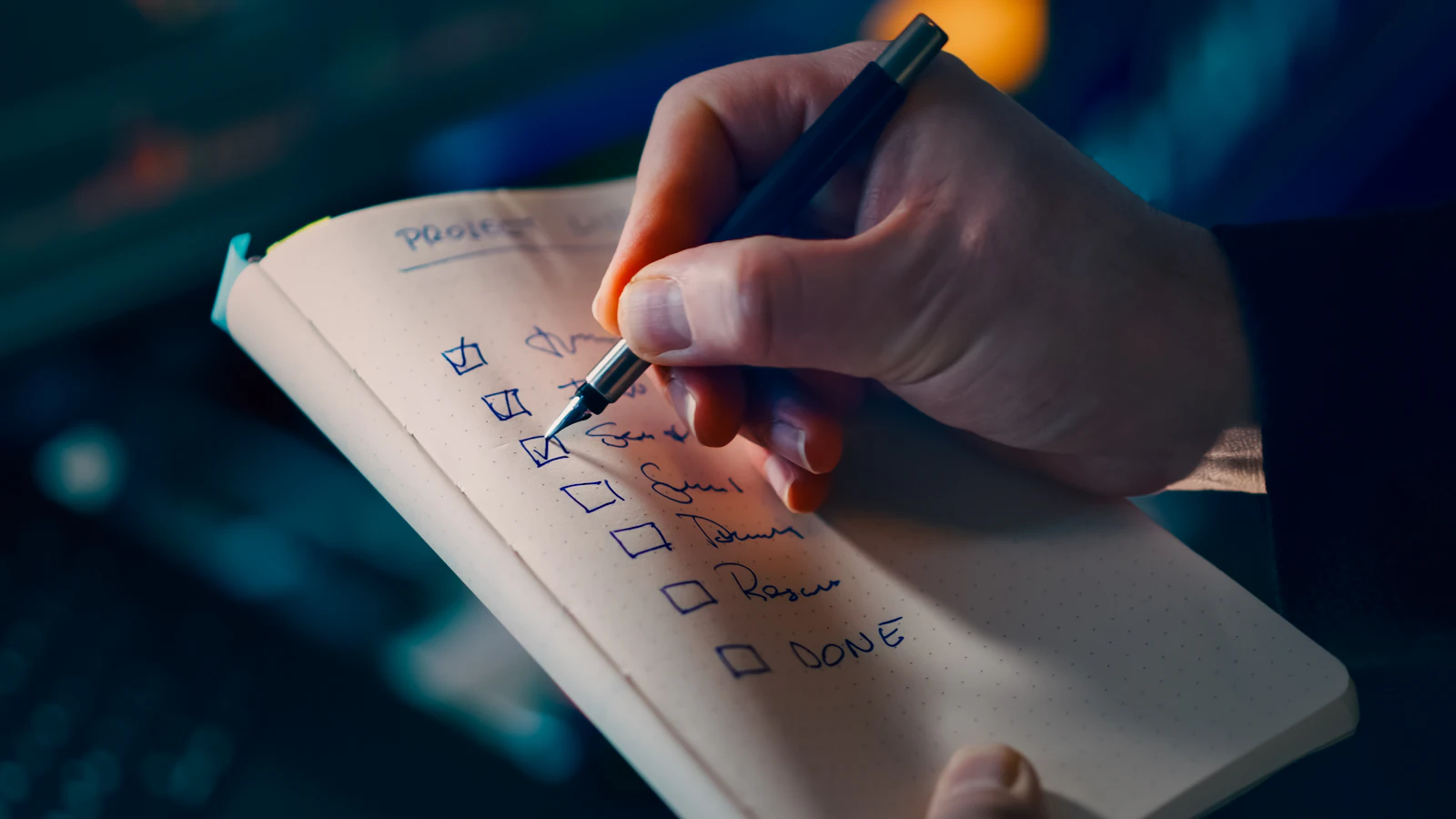 A hand ticking items off a checklist in a paper notebook